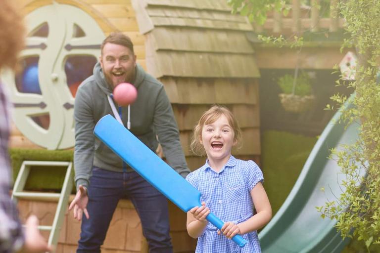 Two adults and a child playing cricket together