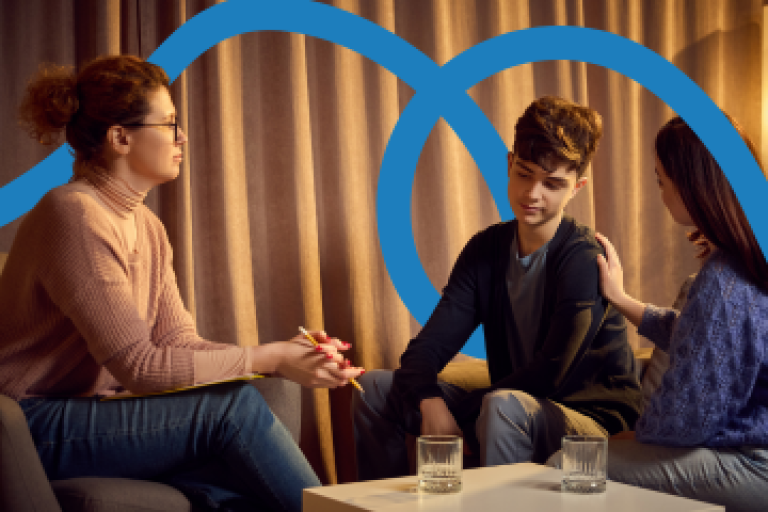 A boy sitting on a sofa, talking to two women.