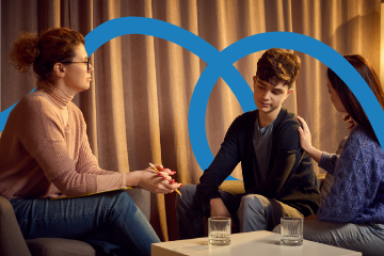 A boy sitting on a sofa, talking to two women.