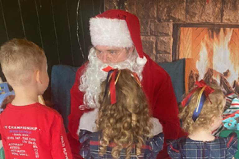 Three children talking to Santa Claus.