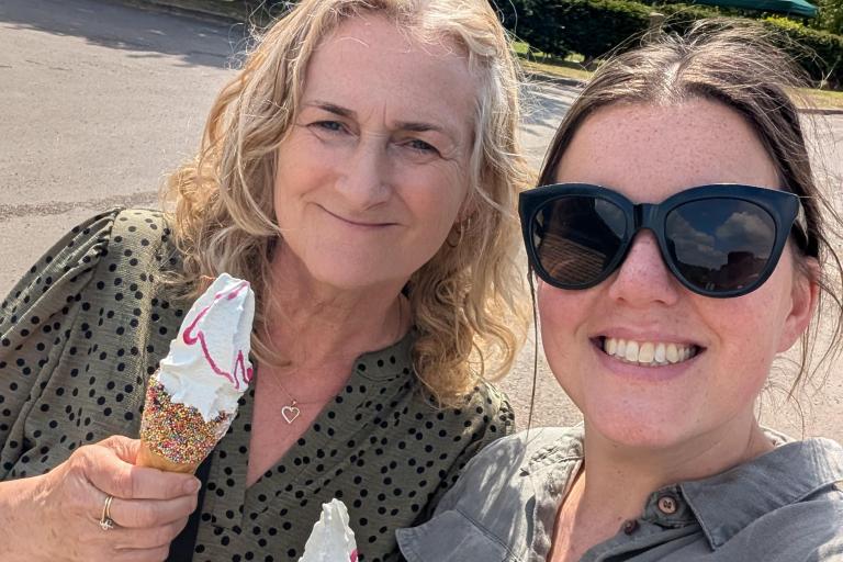 Two women pose for a selfie photo, holding ice creams.