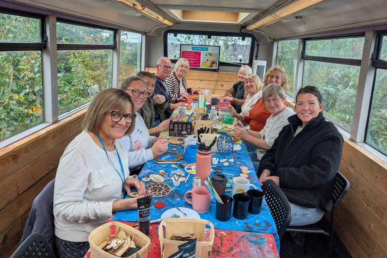 A group of men and women seated at a table, taking part in arts and crafts.