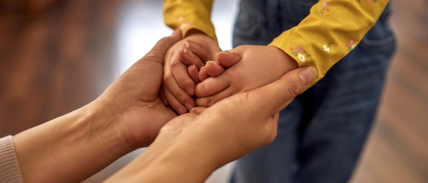 Adults hands cupping a child's hands