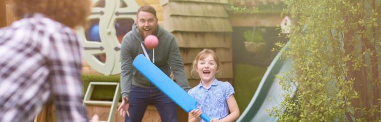 Two adults and a child playing cricket together
