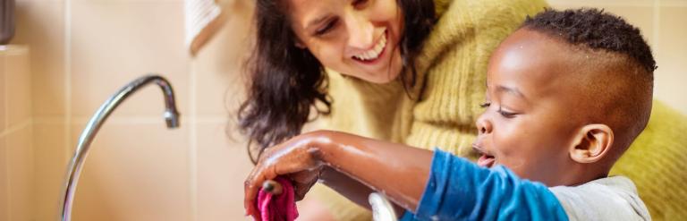 Woman and child washing up at a sink